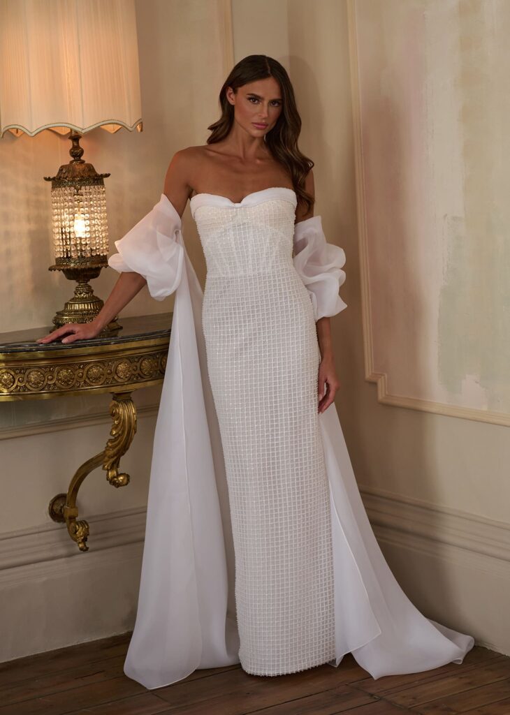 Make a statement in minimalist sophistication with the “Modern Grace” gown. This strapless column silhouette features a structured grid-textured bodice that contours the figure effortlessly.