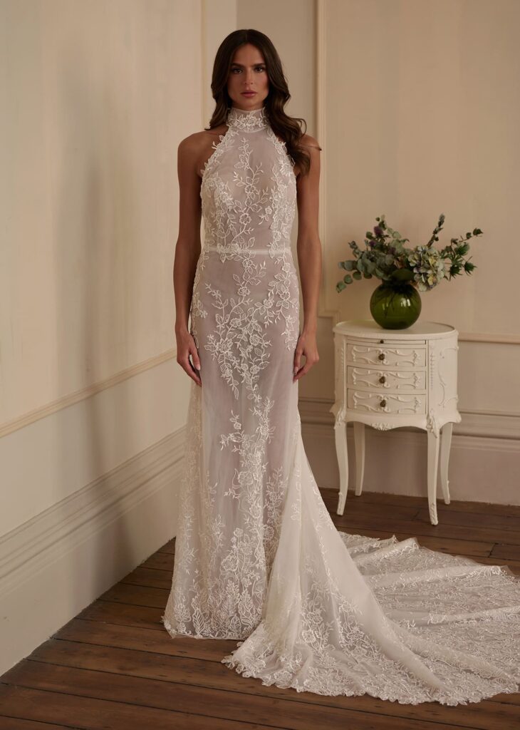 A high-neck halter sheath gown crafted from delicate illusion tulle and adorned with intricate floral lace embroidery.